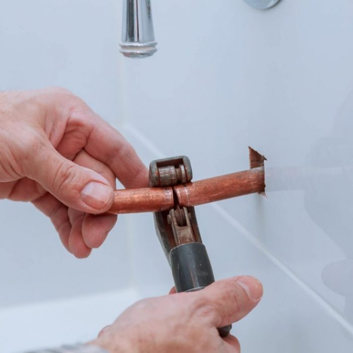 hand-of-working-cutting-copper-pipe-plumbing-e1650583663301.jpg